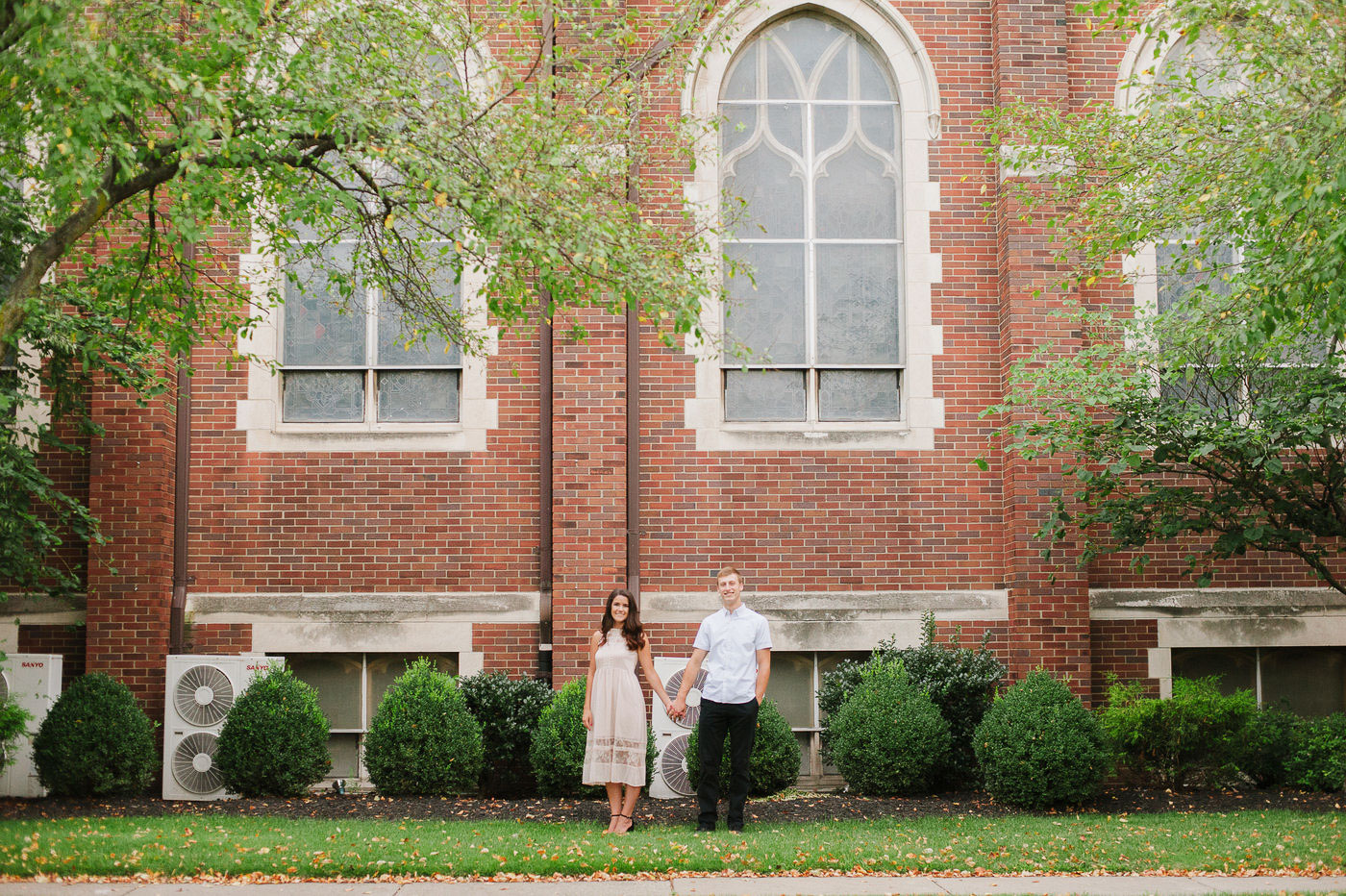 engaged couple standing in front of old brick church