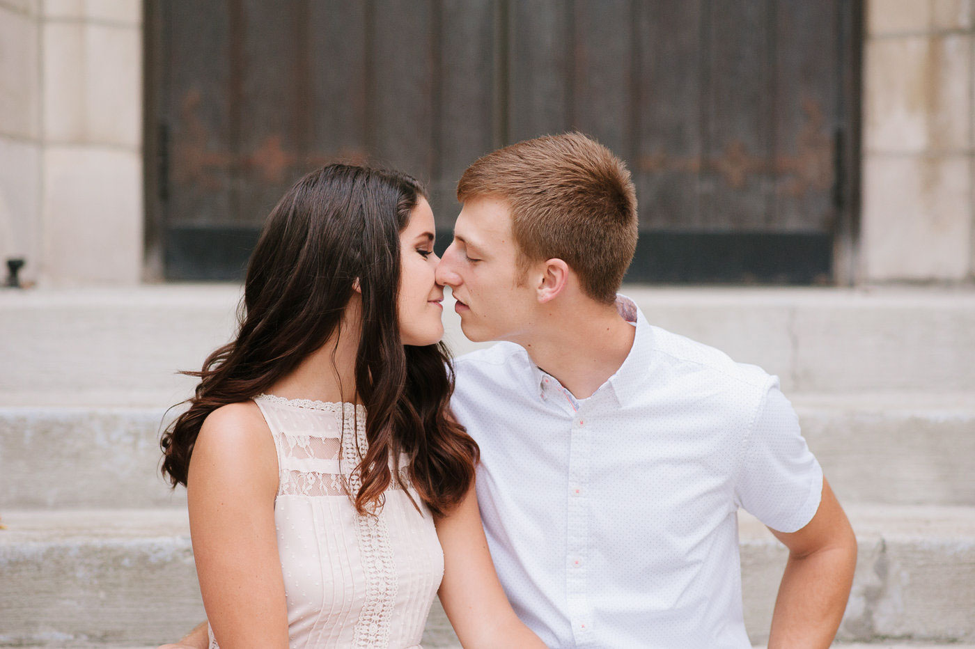engaged couple kissing on church steps
