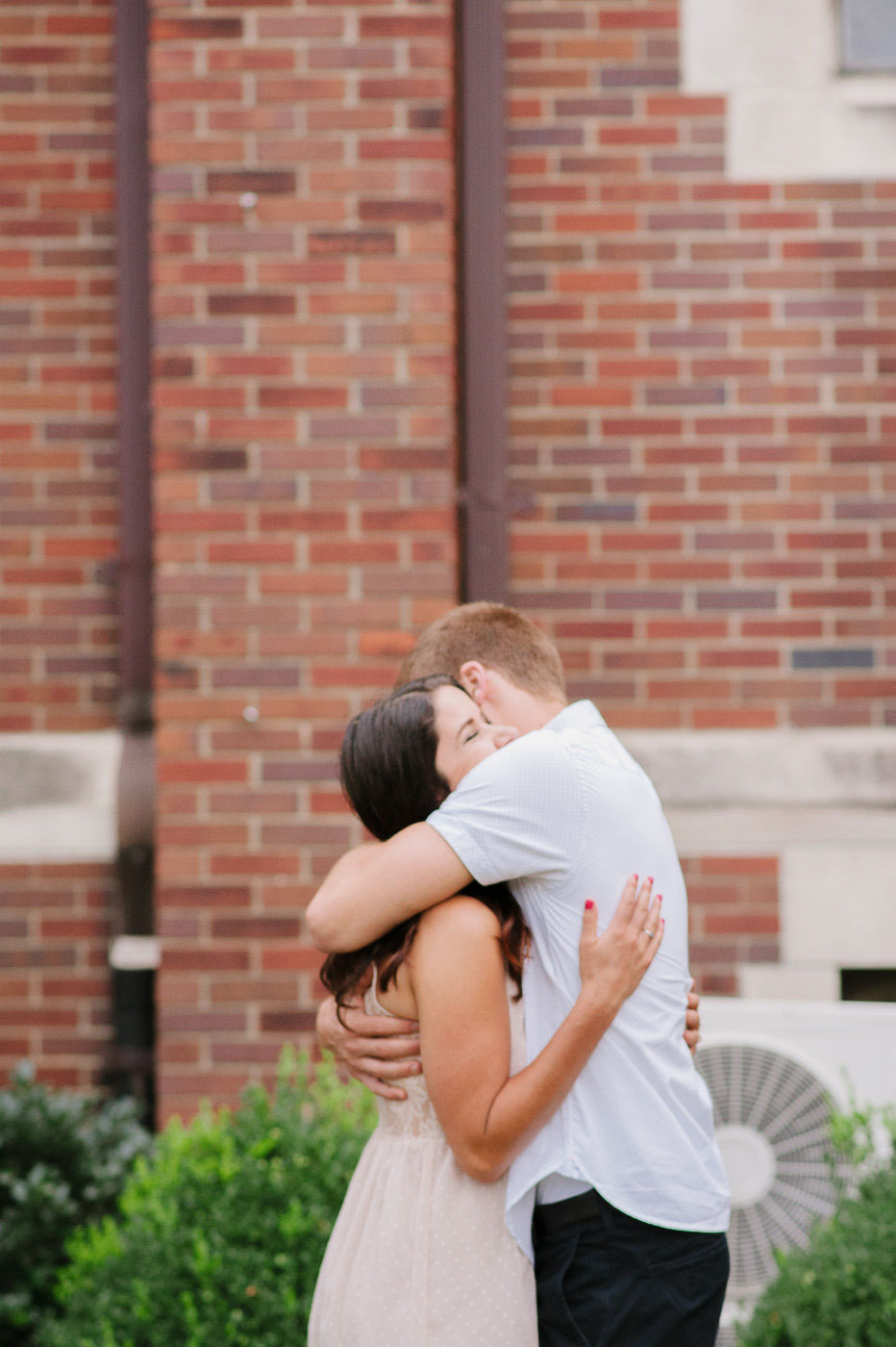 engagement couple hugging in front of brick church