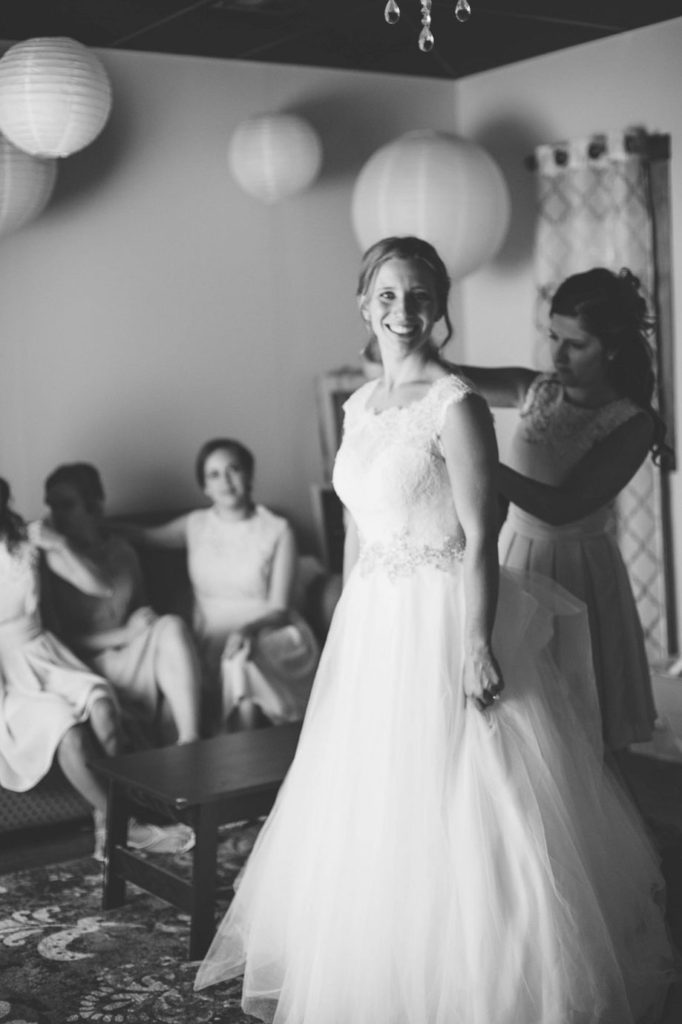 black and white image of bride getting into her wedding dress