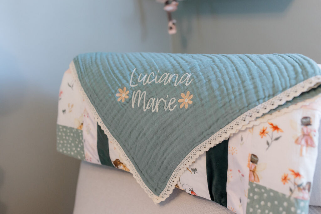 Personalized baby quilt draped over a nursery chair, showcasing meaningful nursery details captured during in-home newborn photos by a Cleveland family photographer.