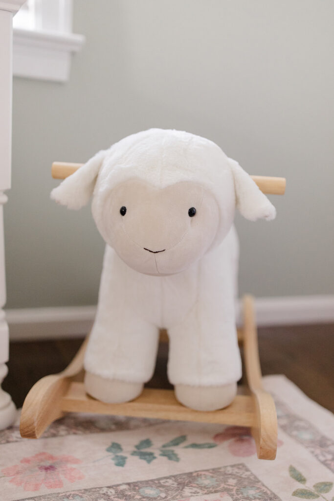 Plush lamb rocking toy in a cozy nursery, highlighting thoughtful nursery details often included in lifestyle newborn photos.