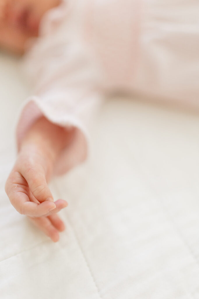 Close-up of a newborn's tiny hand resting on a bed, highlighting the meaningful details often captured during newborn photos.