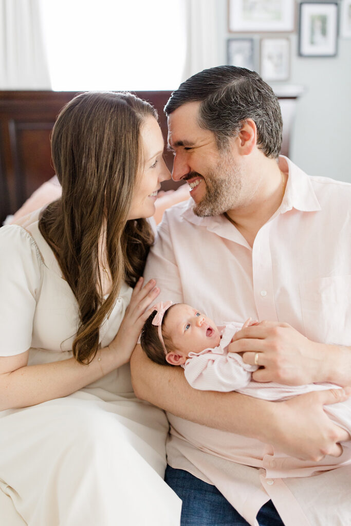 Parents in coordinated neutral outfits cuddle their newborn during an in-home session, showcasing timeless what to wear inspiration from a Cleveland family photographer for heartfelt newborn photos.