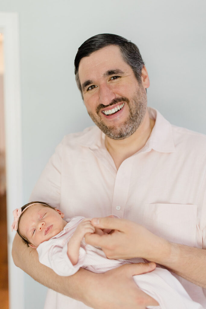 Father holding his newborn while wearing a soft neutral button-down, providing classic what to wear inspiration for natural newborn photos by a Cleveland family photographer.