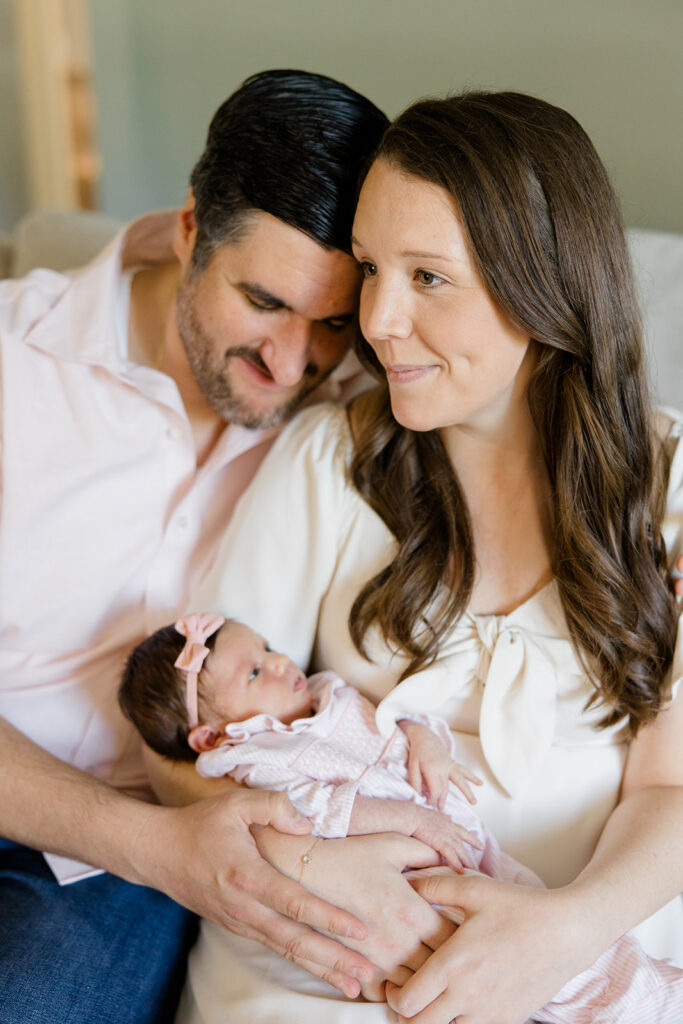 mother and father sitting on the side of their bed while holding their newborn photographed by Cleveland newborn photographer
