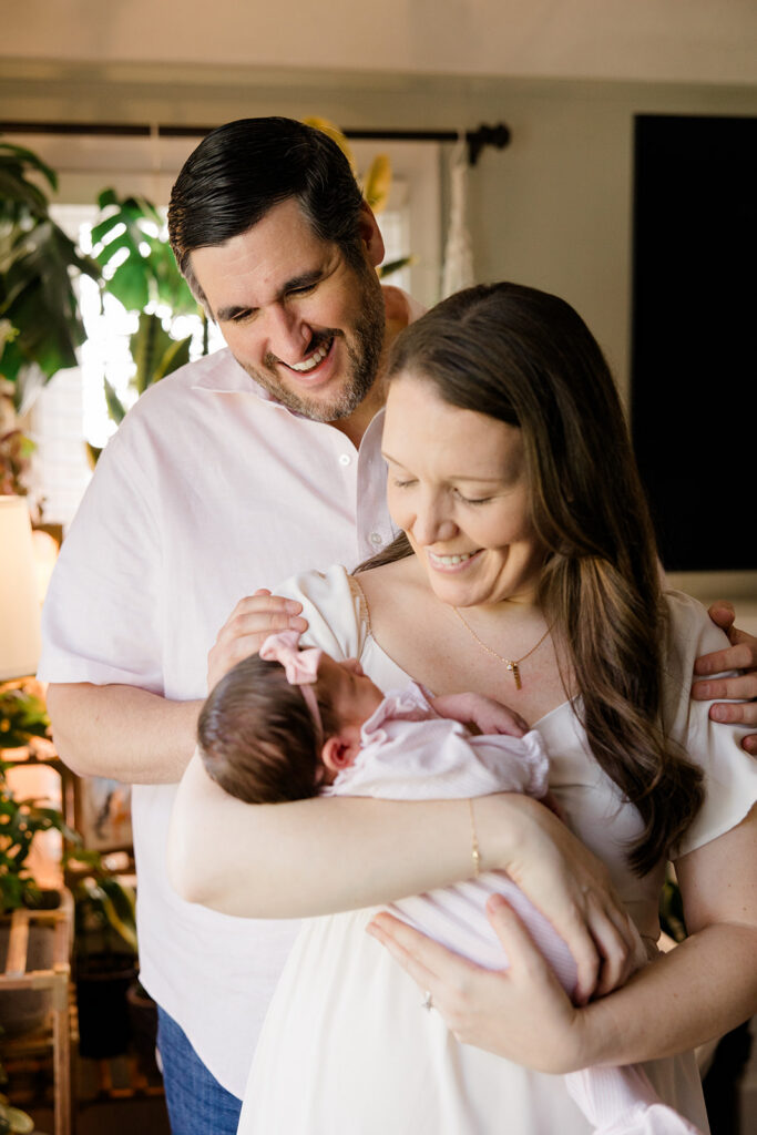 Parents in coordinated neutral outfits admire their newborn together, capturing a warm family moment with classic what to wear inspiration for natural newborn photos by a Cleveland family photographer.