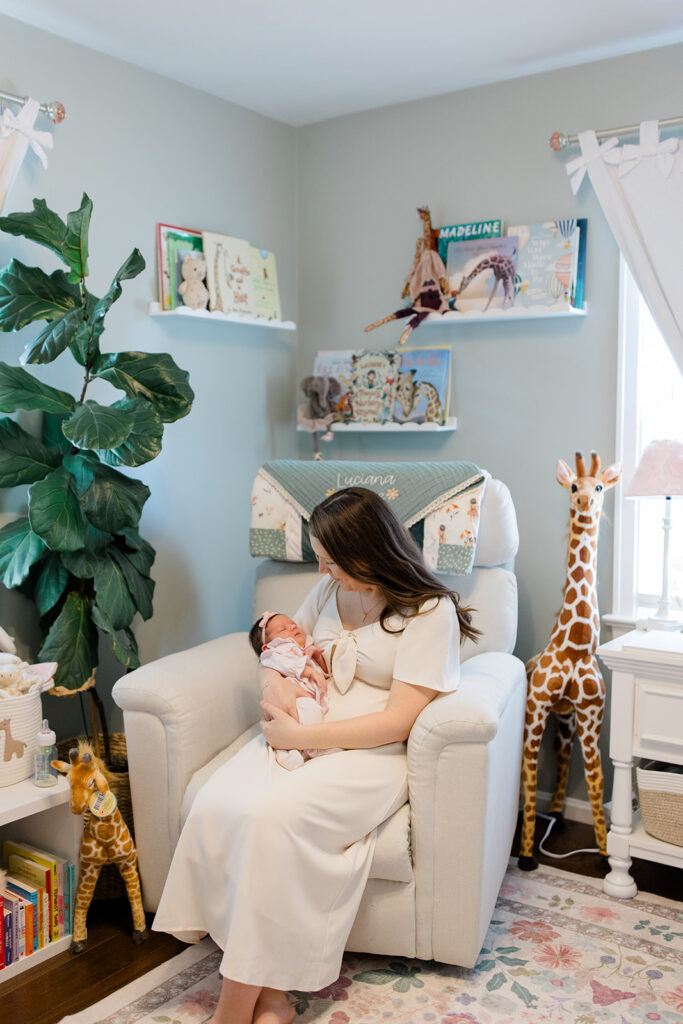 Mother cuddles her newborn in a beautifully decorated nursery, wearing a soft neutral dress that offers timeless what to wear inspiration for in-home newborn photos by a Cleveland family photographer.