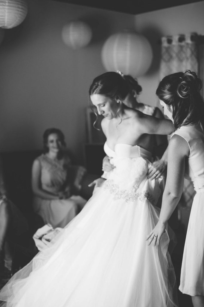 black and white image of bridge getting into her wedding dress