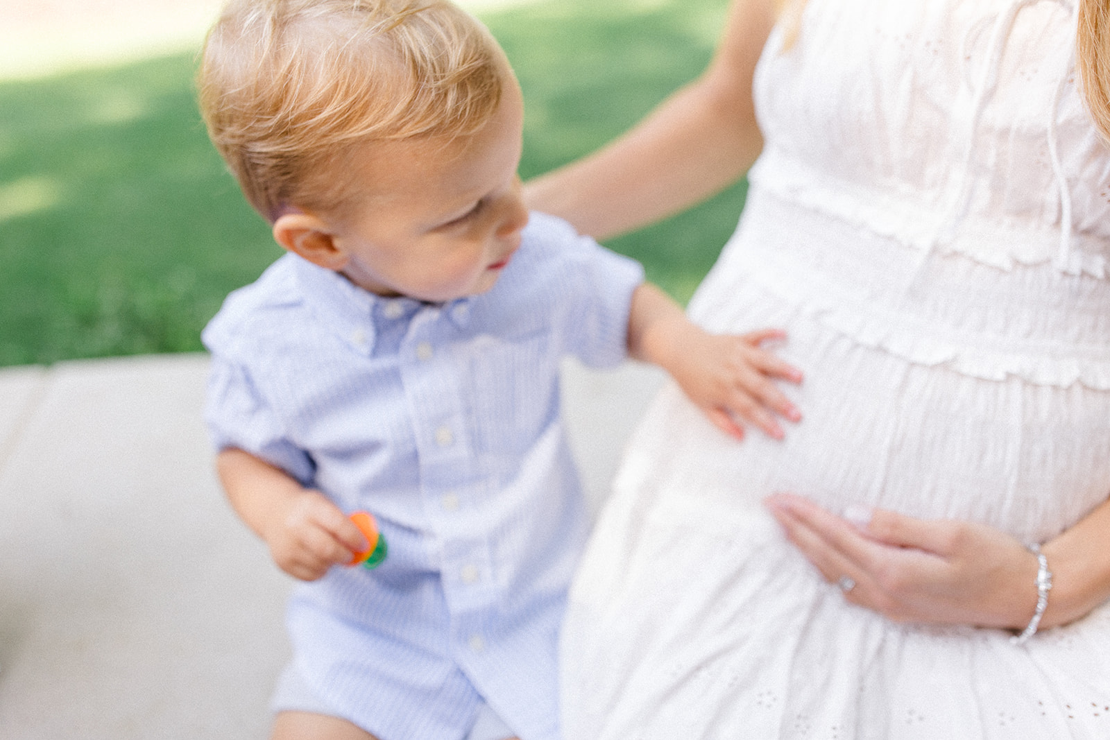 Young boy touching his mother’s pregnant belly during summer family photos, captured by a Cleveland family photographer.
