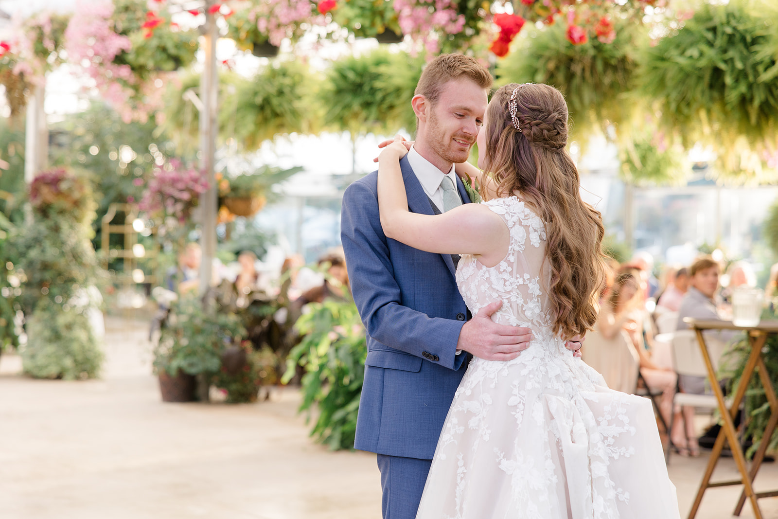 Bride and groom sharing their first dance beneath hanging greenery and flowers at a Mohican Gardens & Conservatory Wedding, captured by a Cleveland wedding photographer