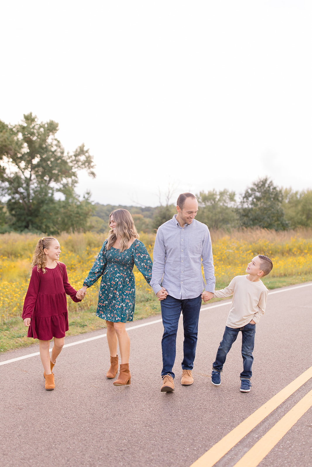 Smiling family sitting on a blanket in front of a white barn, with parents and children closely gathered at Himelright Lodge photographed by Akron family photographer