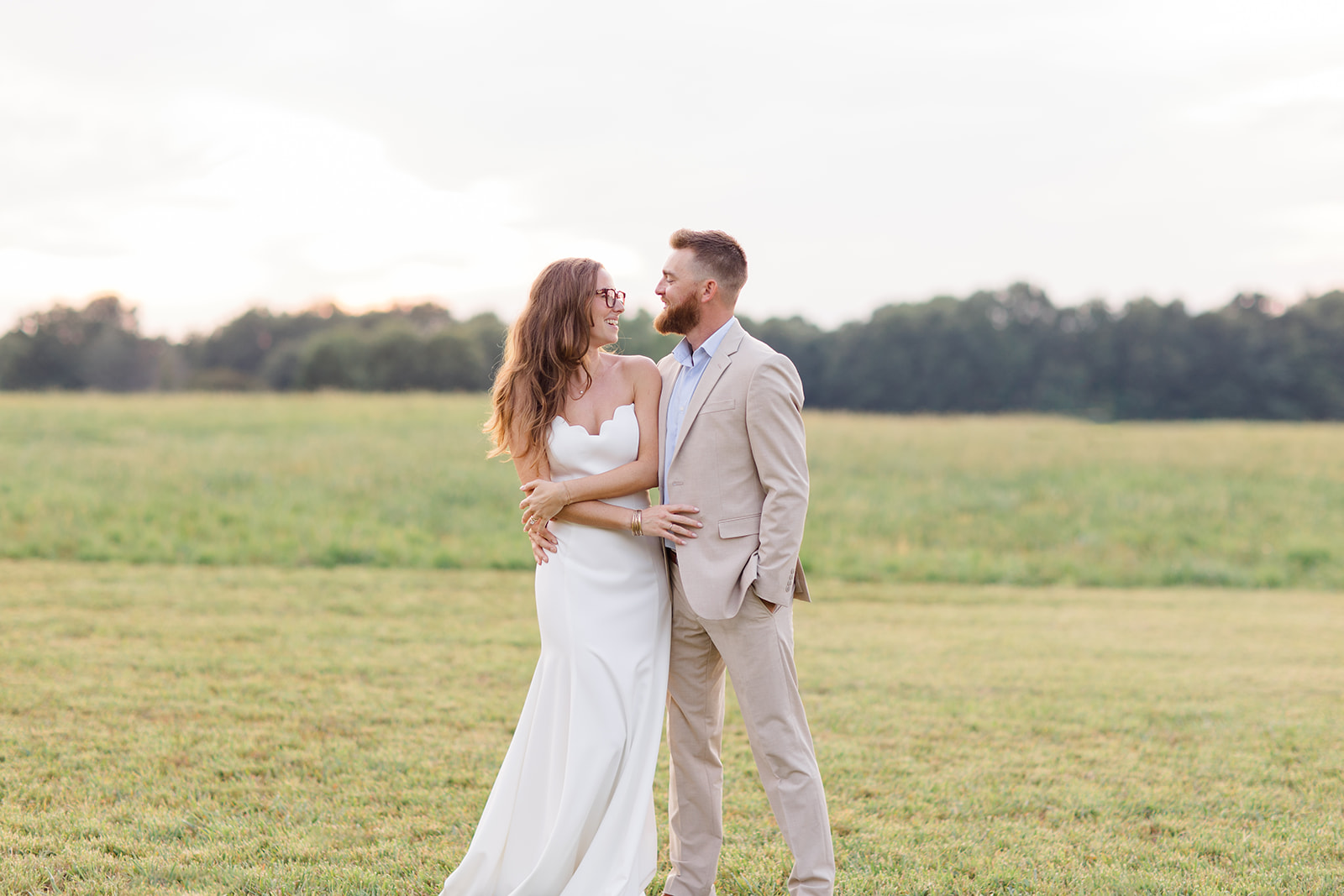 Bride and groom standing together in an open field at sunset, captured by a Cleveland wedding photographer during a wedding at a Cleveland wedding venue.